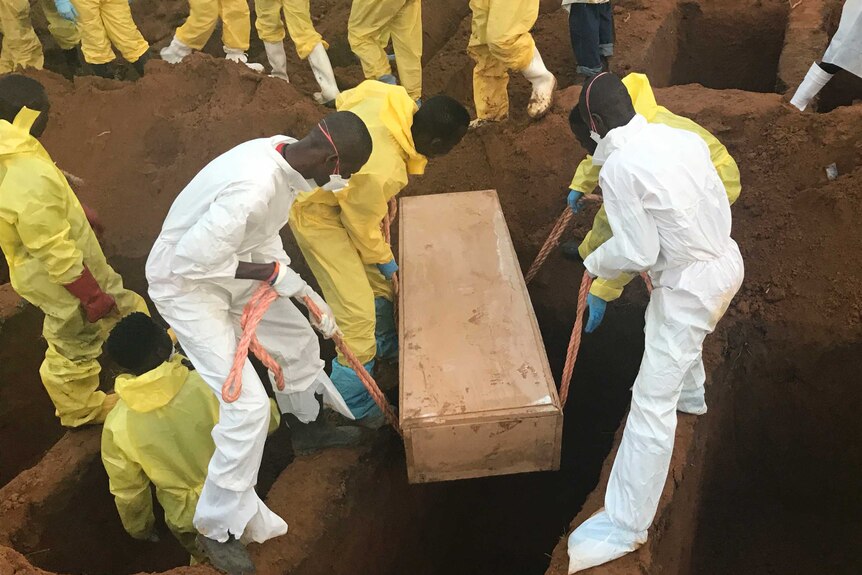 Volunteers lower a coffin into a hole they dug during a mass funeral for victims of heavy flooding and mudslides in Regent.