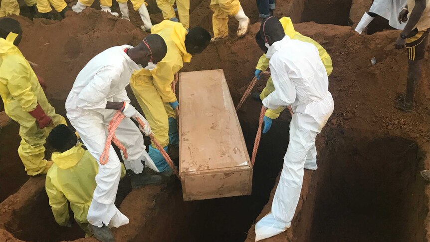 Volunteers lower a coffin into a hole they dug during a mass funeral for victims of heavy flooding and mudslides in Regent.