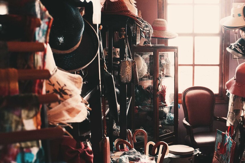 Cluttered room with hats, umbrellas, cabinets, bags, etc depicting the amount of clutter one person can accumulate in a life.