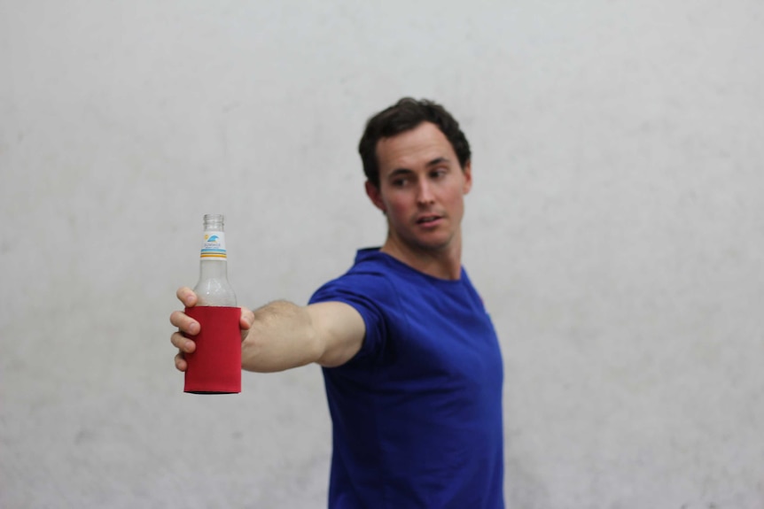 A man holds a beer bottle aloft as he practices yoga