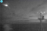 A meteor is captured crossing the night sky by a camera on the ship's bow.