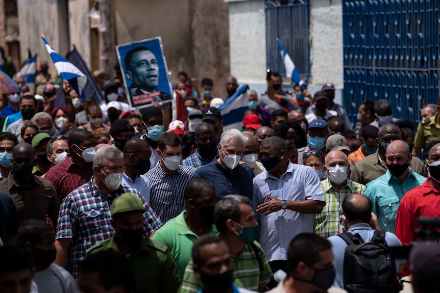 President Miguel Diaz Canel surrounded by crowds holding his poster and flags