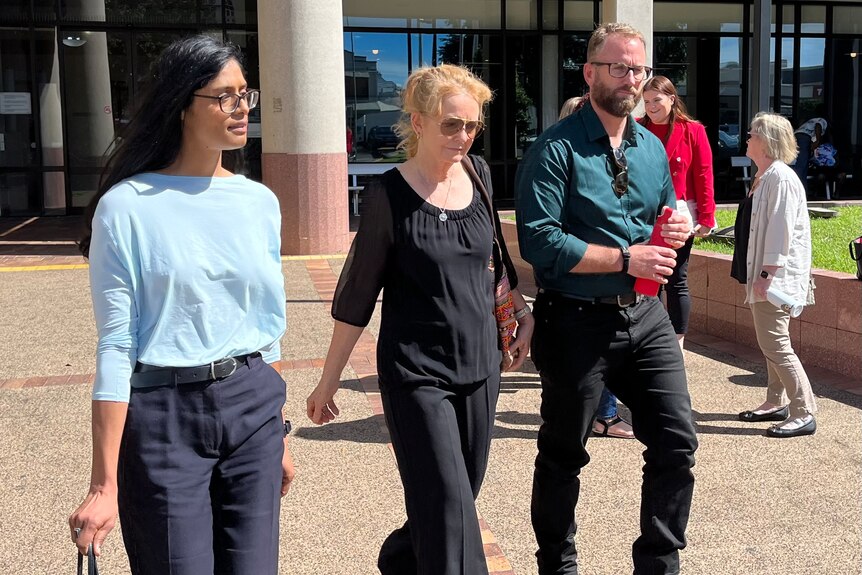 Three people walking outside court