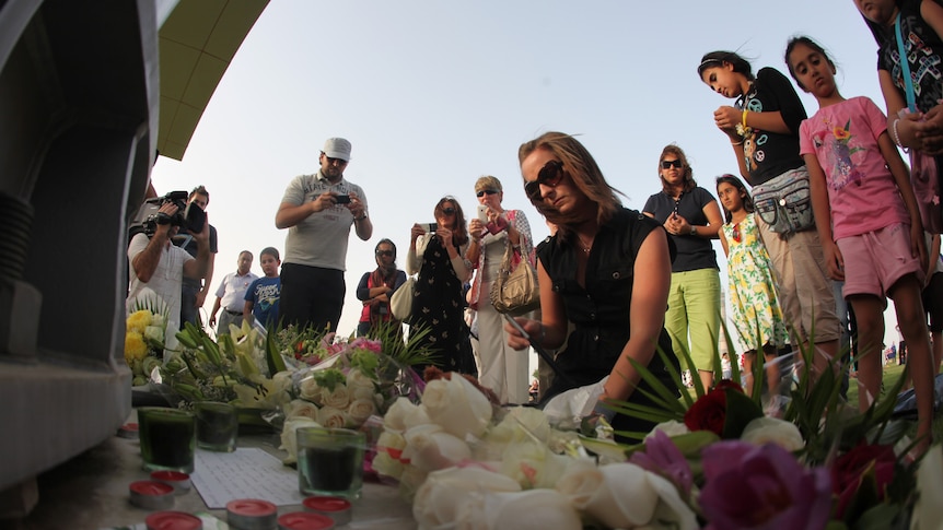 Flowers, toys and candles are laid at a memorial for the victims of a massive shopping centre fire in Doha.