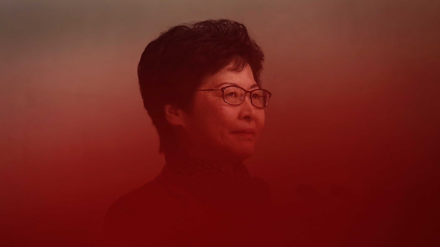 A woman with black hair and black-rimmed glasses is seen through a red gradient.