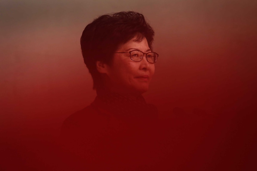 A woman with black hair and black-rimmed glasses is seen through a red gradient.