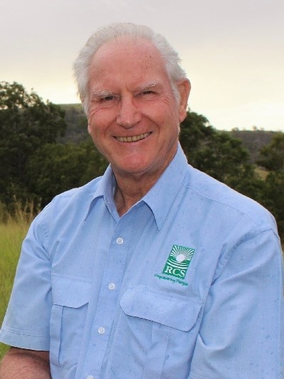 Older man with grey hair and blue shirt smiling