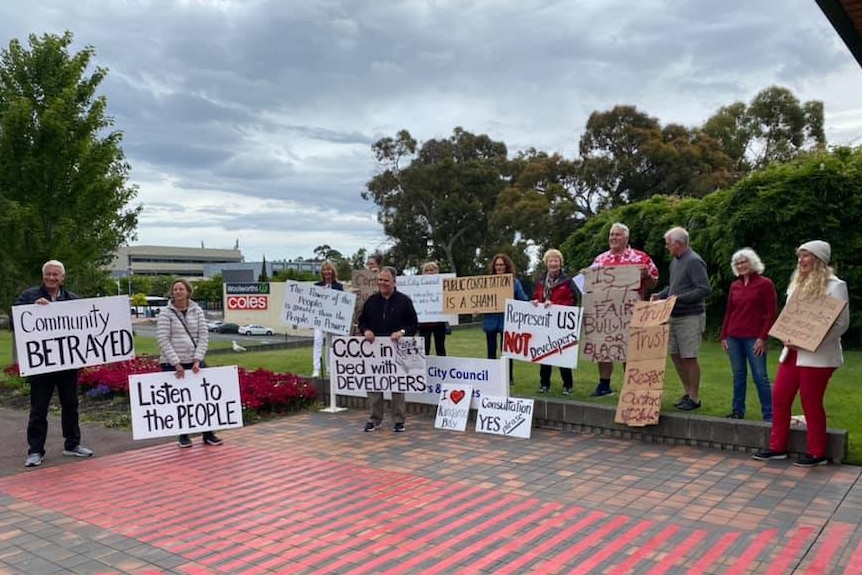 About a dozen people hold signs protesting a development on Hobart's eastern shore