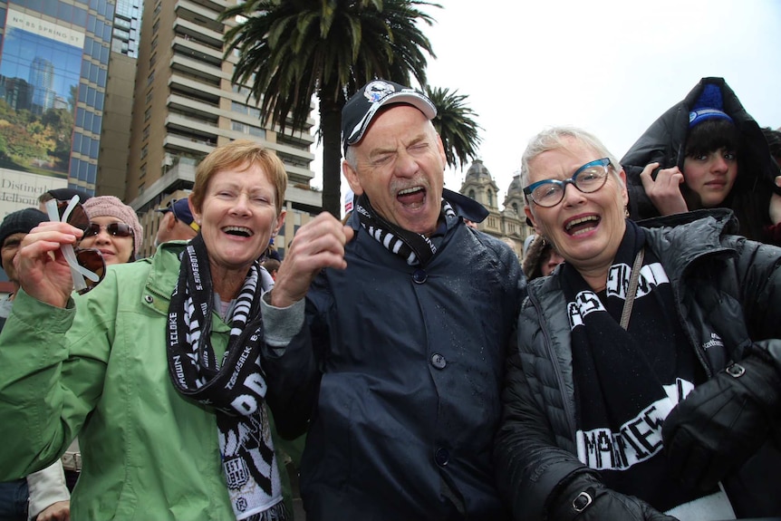Three Collingwood fans at the AFL grand final parade.