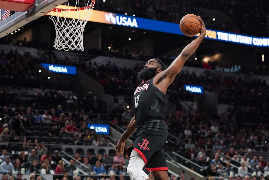 James Harden winds up for a slam dunk, leaping up with the ball in one hand