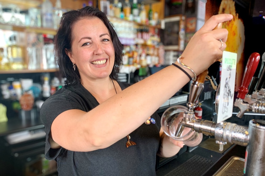 Sarah Janssen smiling and pouring a beer.