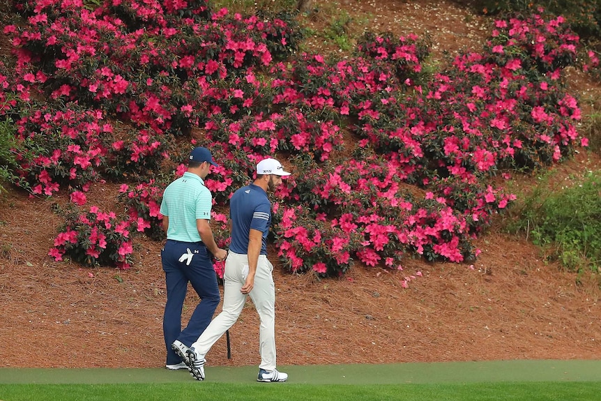 Gary Woodland (L) and Dustin Johnson walk past some azaleas at Augusta ahead of the 2017 Masters.