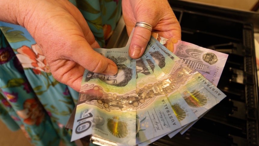 Lady's hand holding cash over the till