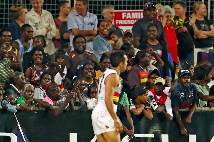 Fans are in focus as they watch Eddie Betts, blurry in the foreground, during an Adelaide Crows AFL match in Darwin.
