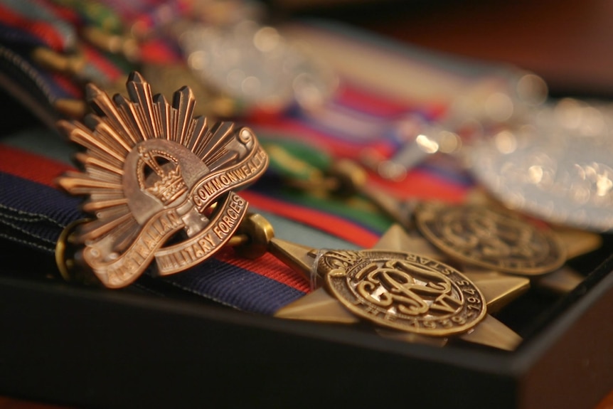 A black box with four medals with ribbons attached to them