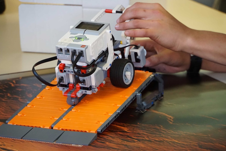 A Lego robot sits at the top of a ramp.