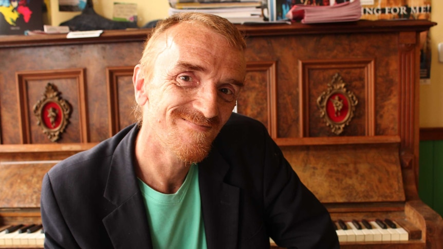 Bill Longo sitting at a piano in a Hobart cafe.