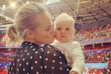Jenni Screen kisses her daughter Edith while at a basketball game.
