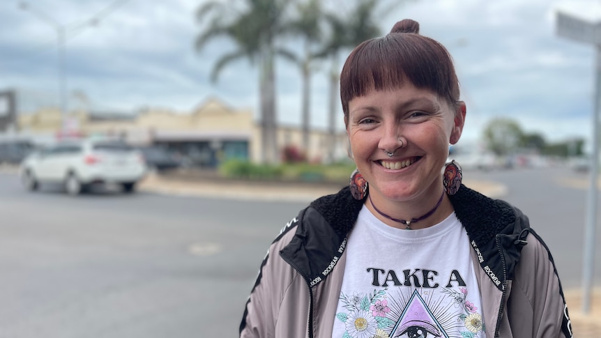 A women stands on the side of a street with a big smile on her face 