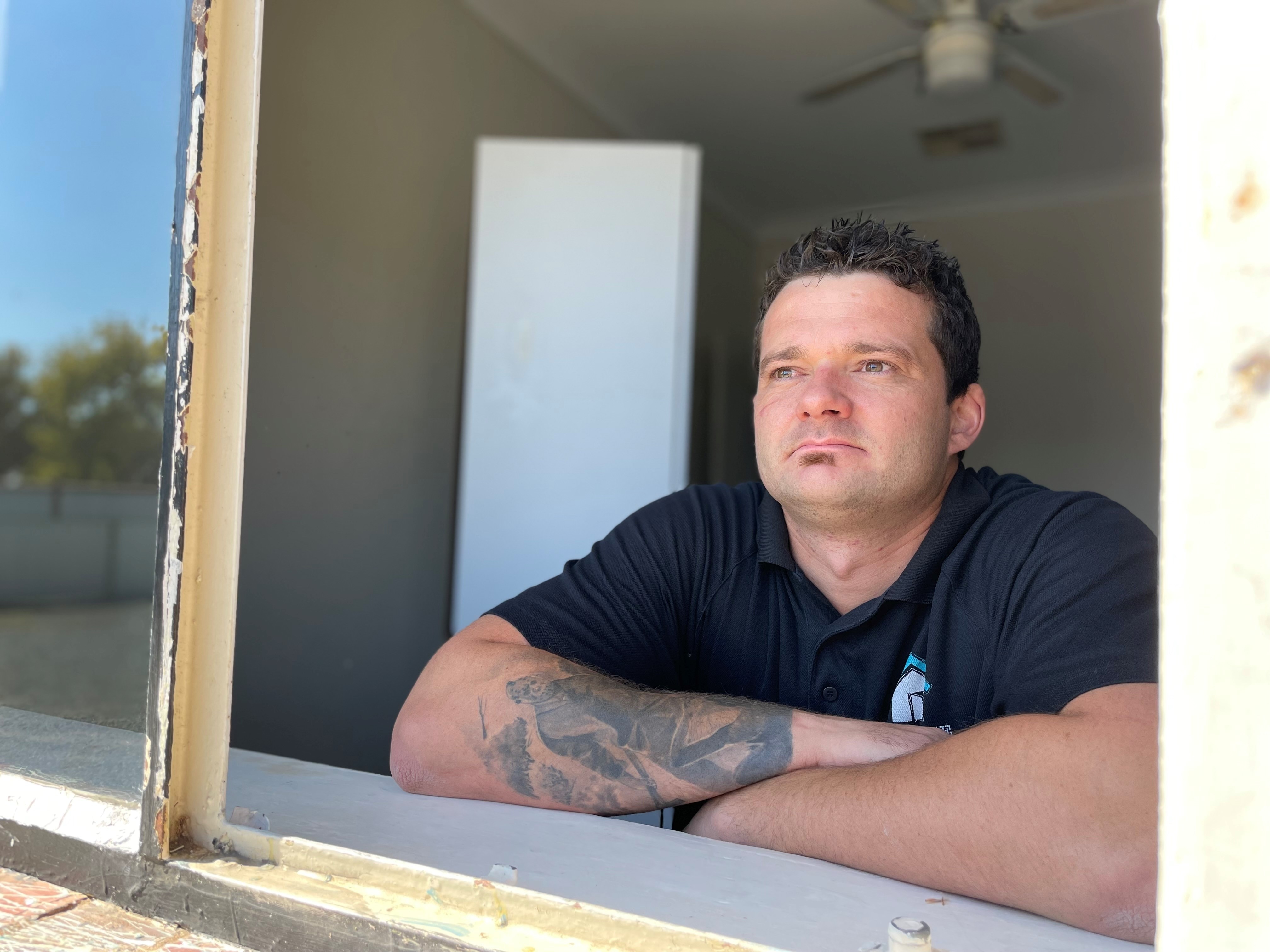 A man leaning on a window sill looking outside