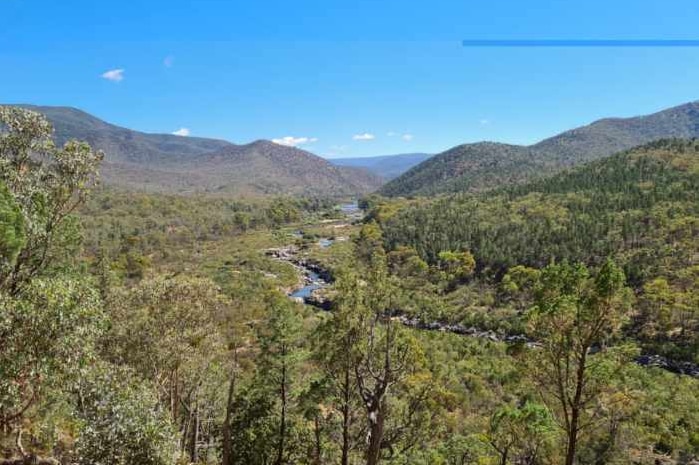 A picturesque photograph of a valley with the Snowy River and blue skies.
