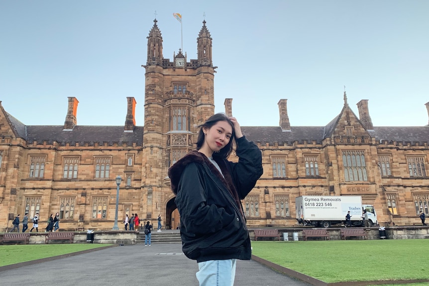 A photo of a young woman in front of a sandstone building.