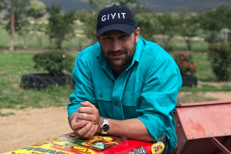 NSW Drought relief manager Scott Barrett leaning over a few backs of dog food.