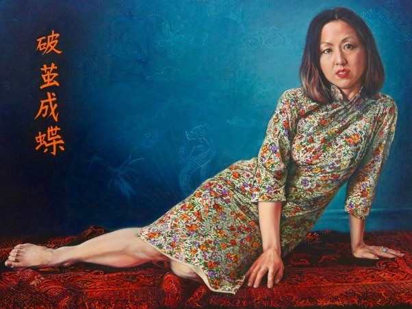 A portrait of a woman leaning on a red blanket.