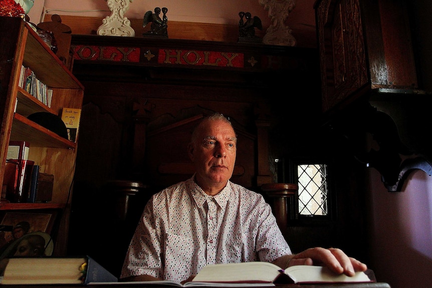 Photo of Fabian LoSchiavo at home, surrounded by books and religious iconography.