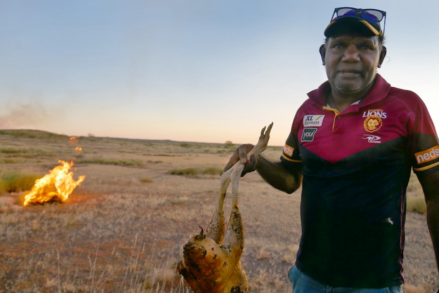 An Indigenous man holding a dead bush turkey. 