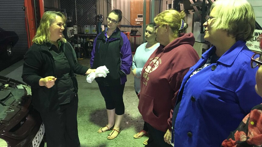 The women learn how to check the oil level from Miriam Monteith.