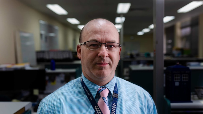 Police man with glasses standing in front of dark room