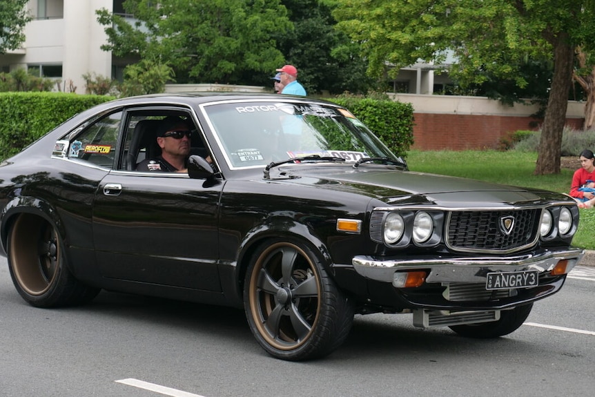 A man driving a black car in Canberra.