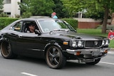 A man driving a black car in Canberra.
