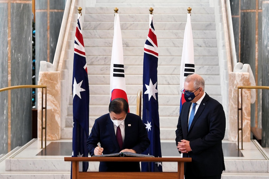 Scott Morrison watches on as South Korean President Moon Jae-in signs the official visitors book at Parliament House.