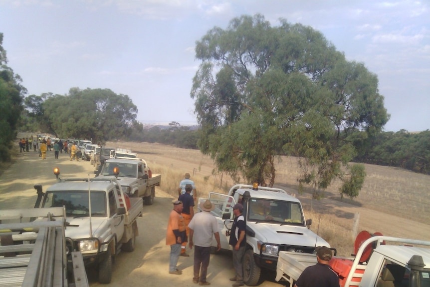 A convoy of utes with water pumps on a dirt country road.