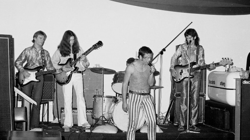 Black and white photo of four men performing in a band