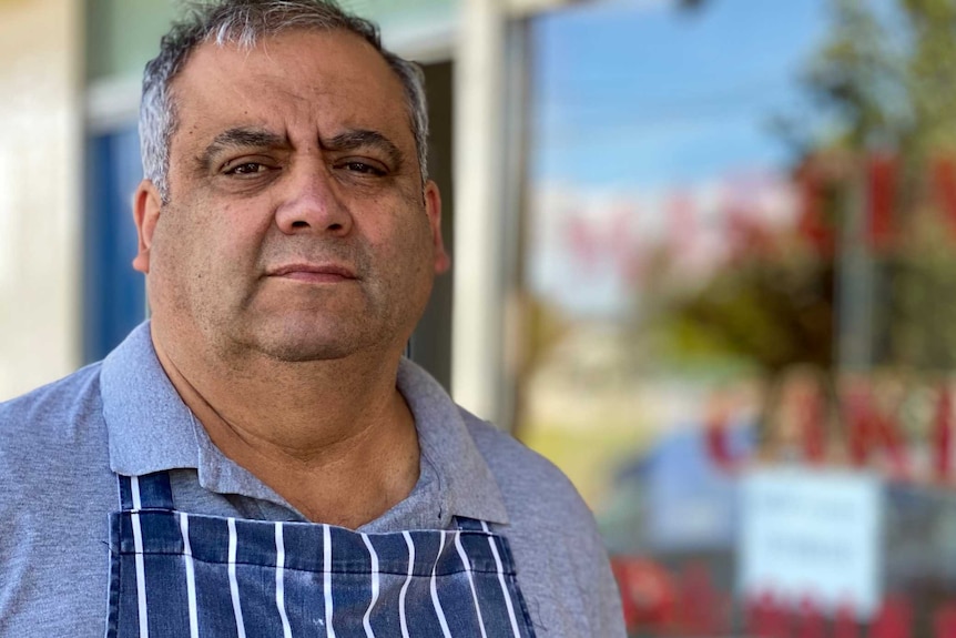 A man stands outside a cake shop.