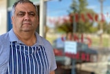 A man stands outside a cake shop.