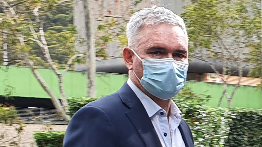 Former MP Craig Thomson, in a suit and mask, heads into Gosford Local Court. Jan 2022