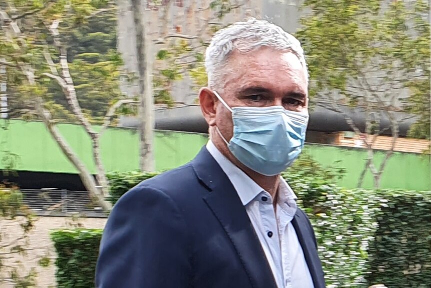 Former MP Craig Thomson, in a suit and mask, heads into Gosford Local Court. Jan 2022
