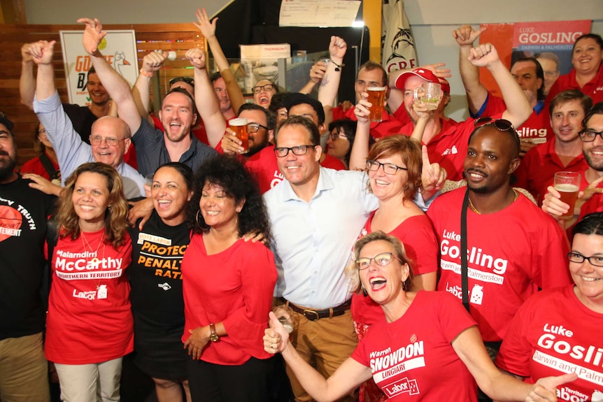 A group of Labor supporters wave their arms.