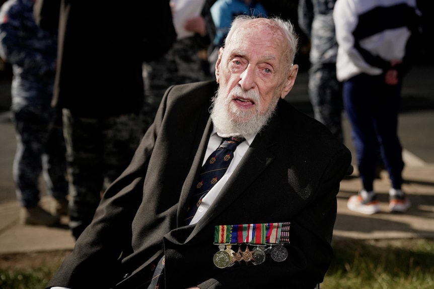 An elderly man with a number of military medals pinned to his jacket.