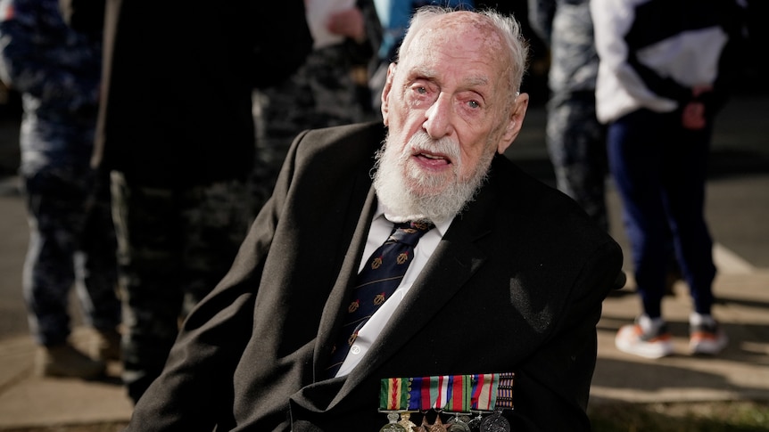 An elderly man with a number of military medals pinned to his jacket.