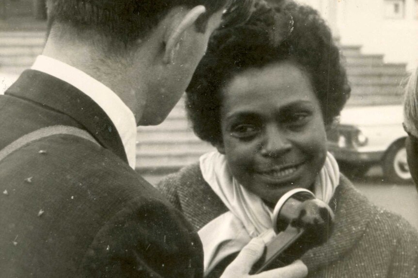 A young woman speaks to a journalist in the street.