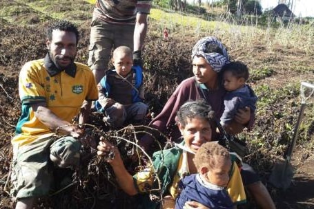 Villagers sit beside damaged crops in PNG