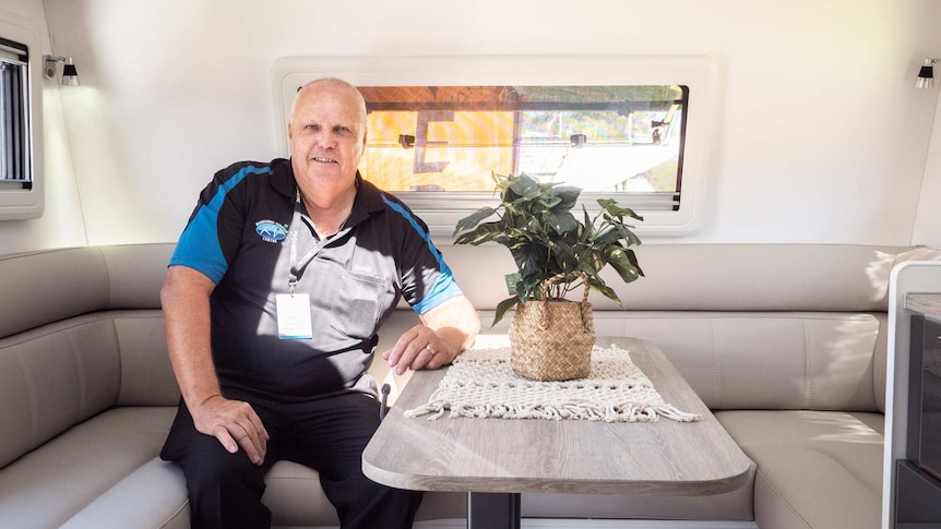 A man sits inside a caravan for sale