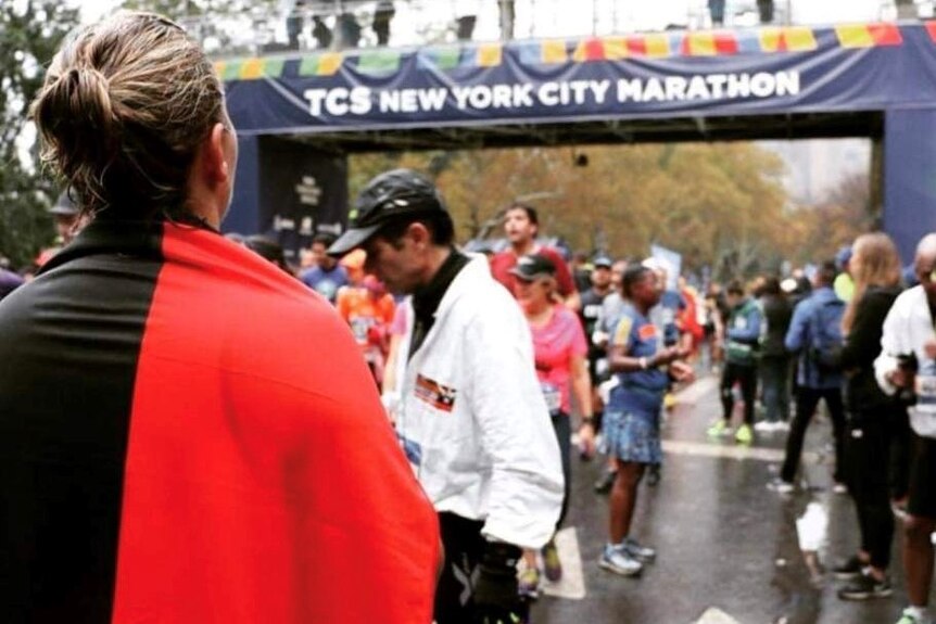 Ms Jennings draped in an Aboriginal flag at the finish line of the New York Marathon.