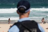 A police officer looks out at patrons on Bondi Beach.
