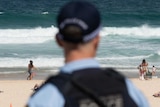 A police officer looks out at patrons on Bondi Beach.